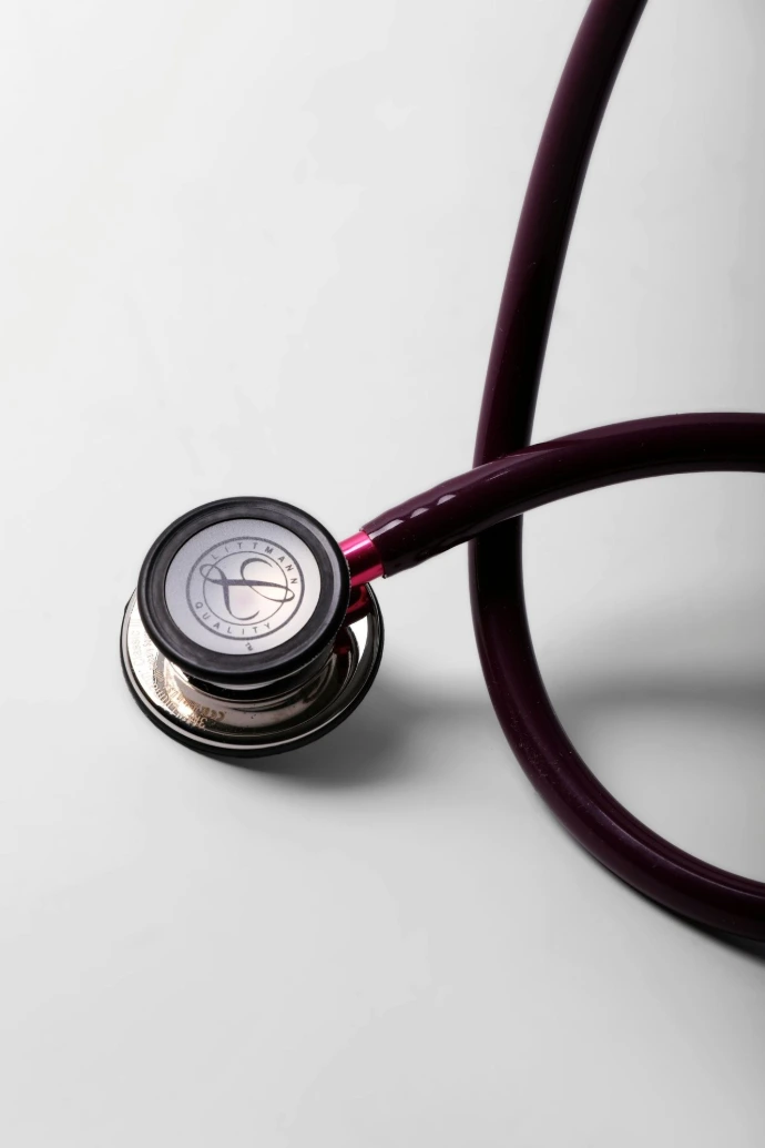A close-up of a burgundy stethoscope on a white surface.
